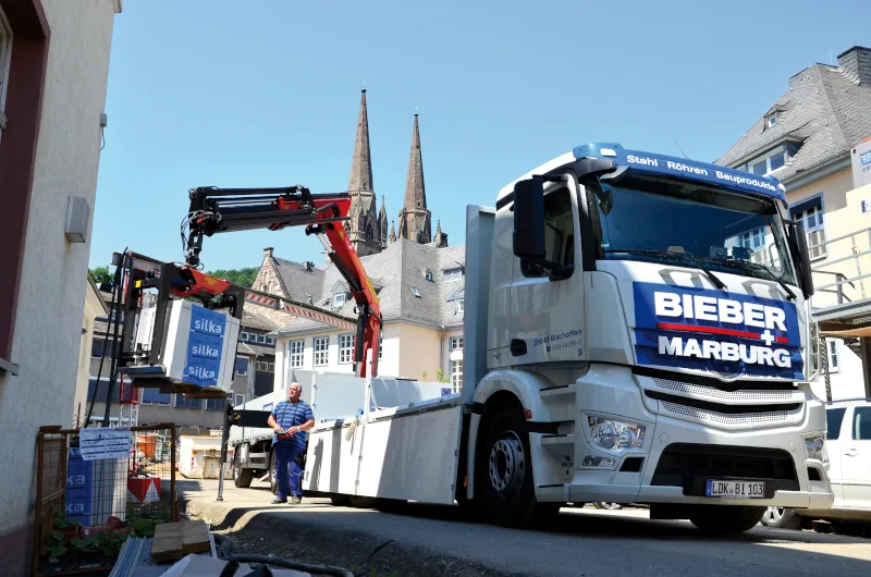 LKW von BIEBER + MARBURG mit Ladekran bei der Materialanlieferung auf einer innerstädtischen Baustelle
